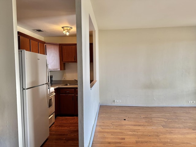 kitchen featuring sink, white appliances, and light hardwood / wood-style flooring