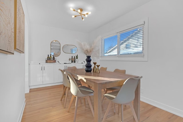 dining area featuring light wood finished floors, an inviting chandelier, and baseboards