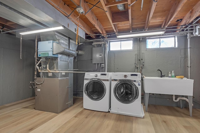 laundry area featuring laundry area, light wood finished floors, electric panel, separate washer and dryer, and a sink