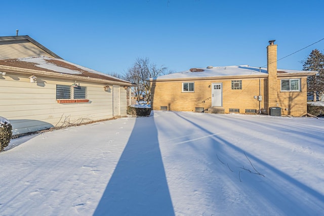 snow covered house featuring entry steps and cooling unit