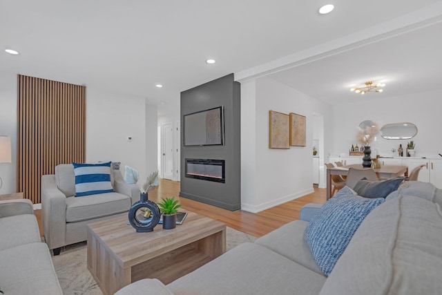 living area featuring a large fireplace, baseboards, light wood-style flooring, and recessed lighting