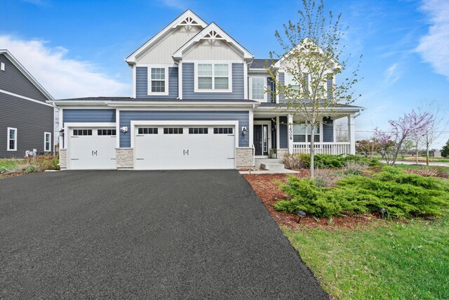 craftsman inspired home featuring a garage, stone siding, board and batten siding, a porch, and driveway
