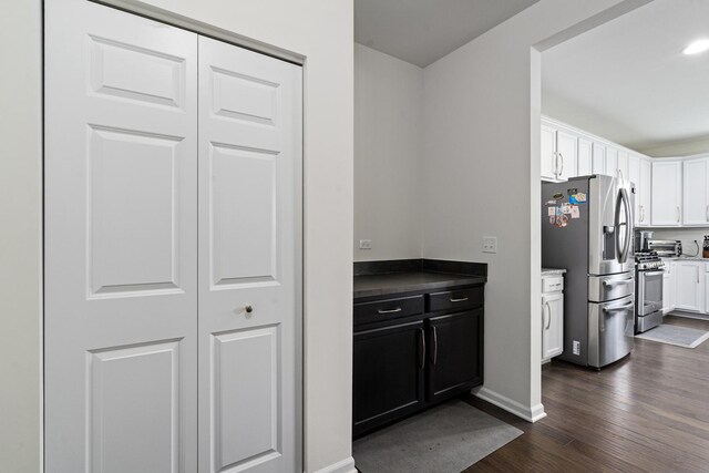 kitchen with baseboards, white cabinets, dark cabinetry, dark wood finished floors, and appliances with stainless steel finishes