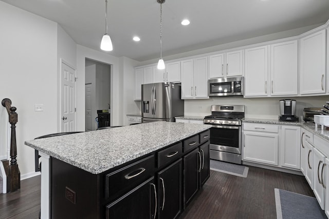 kitchen with dark wood-style floors, a center island, white cabinetry, dark cabinetry, and appliances with stainless steel finishes