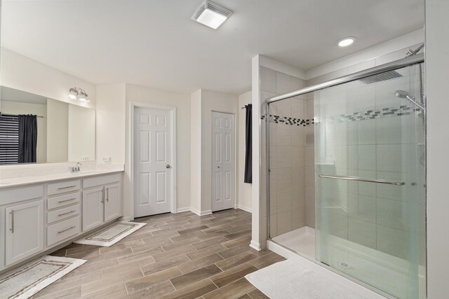 full bath featuring visible vents, a stall shower, wood finished floors, vanity, and baseboards