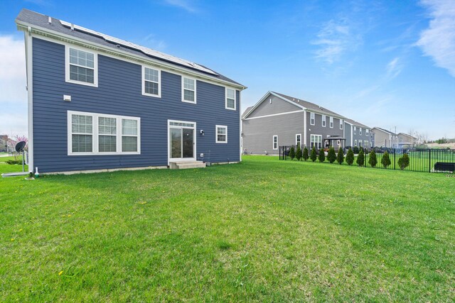 rear view of house with a yard, fence, and entry steps
