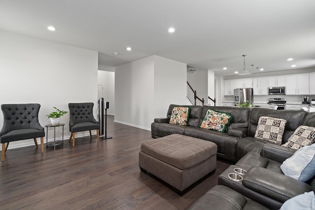 living room featuring recessed lighting, baseboards, dark wood finished floors, and stairs