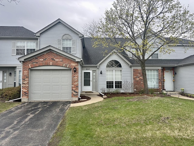 traditional home with an attached garage, aphalt driveway, brick siding, and a front yard