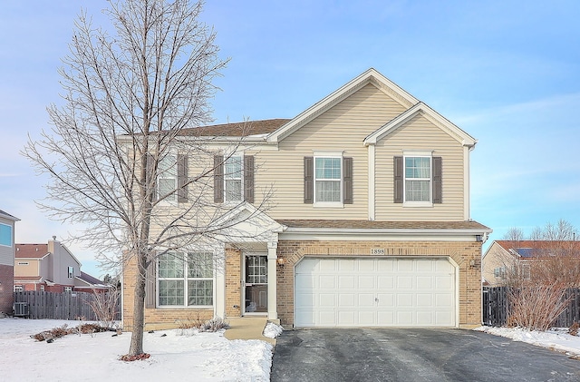 traditional home featuring driveway, a garage, fence, cooling unit, and brick siding