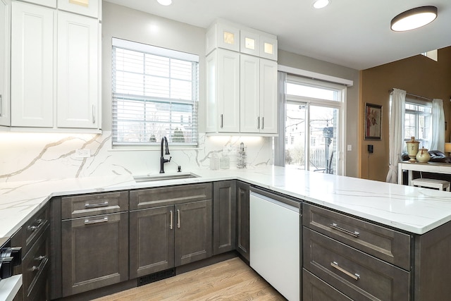 kitchen with glass insert cabinets, a peninsula, white cabinetry, and a sink