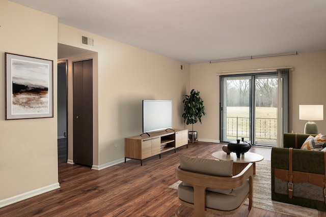 living room featuring dark wood-type flooring, visible vents, and baseboards