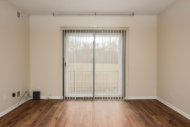 spare room featuring visible vents, baseboards, and wood finished floors