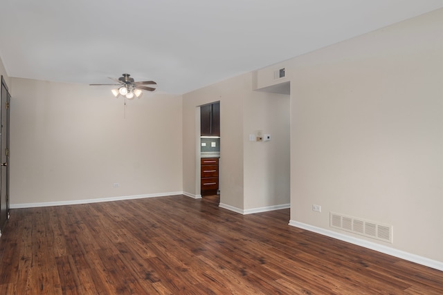 spare room featuring dark wood-style floors, visible vents, and baseboards