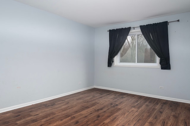 empty room with dark wood finished floors and baseboards