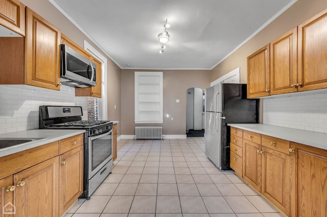 kitchen with radiator, stainless steel appliances, decorative backsplash, light tile patterned flooring, and crown molding