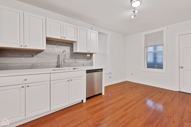 kitchen with sink, light wood-type flooring, dishwasher, white cabinets, and tasteful backsplash