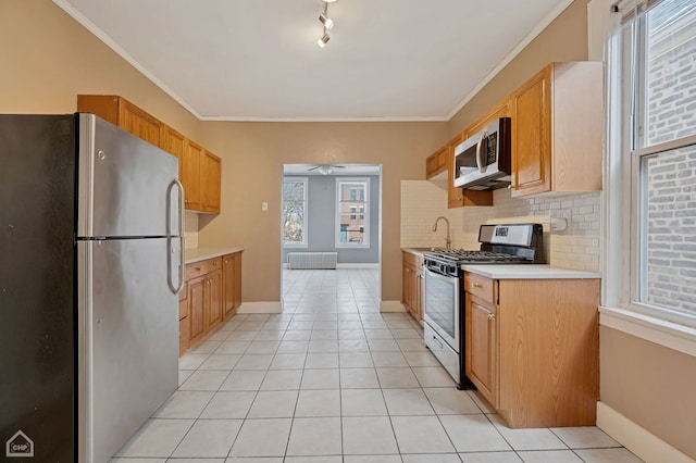 kitchen featuring appliances with stainless steel finishes, plenty of natural light, tasteful backsplash, and crown molding