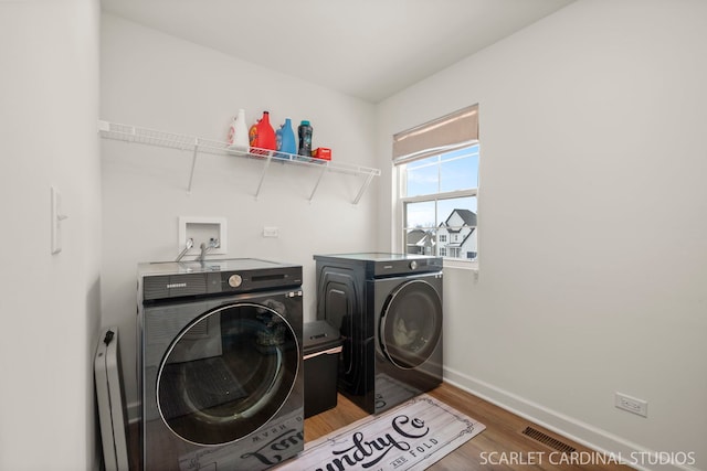 laundry area with independent washer and dryer and hardwood / wood-style floors