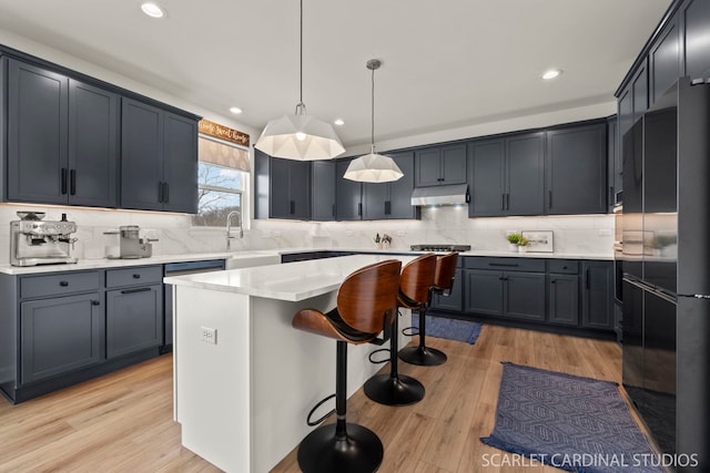 kitchen featuring pendant lighting, sink, light wood-type flooring, and a kitchen island