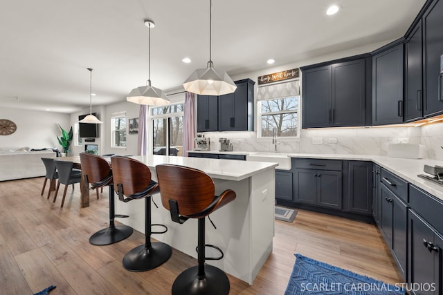 kitchen featuring sink, decorative light fixtures, backsplash, and a kitchen island