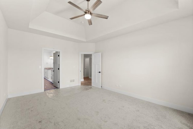 carpeted spare room featuring ceiling fan and a tray ceiling