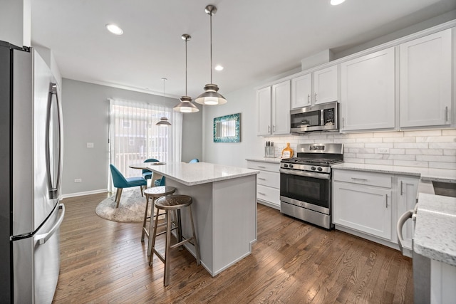 kitchen featuring pendant lighting, stainless steel appliances, a center island, and white cabinets