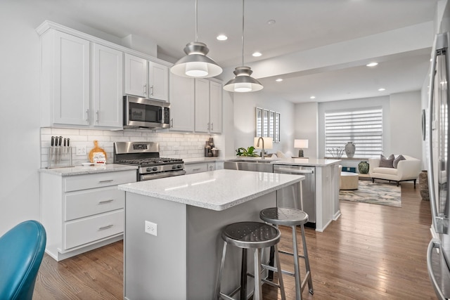 kitchen featuring sink, appliances with stainless steel finishes, white cabinetry, hanging light fixtures, and kitchen peninsula