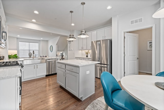 kitchen featuring appliances with stainless steel finishes, decorative light fixtures, a center island, and white cabinets