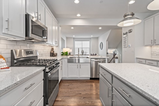 kitchen with sink, white cabinetry, light stone counters, pendant lighting, and stainless steel appliances