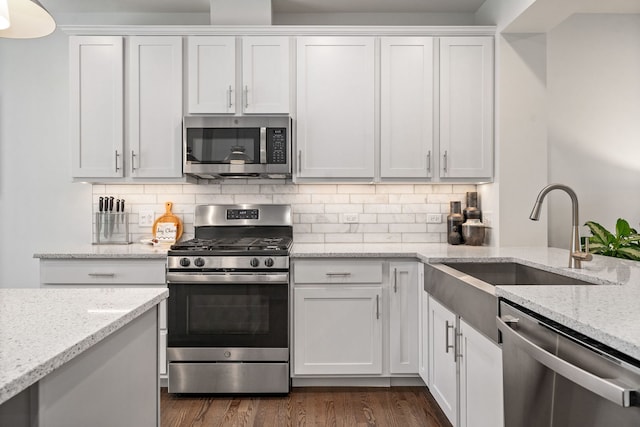 kitchen featuring dark hardwood / wood-style flooring, light stone countertops, white cabinets, and appliances with stainless steel finishes