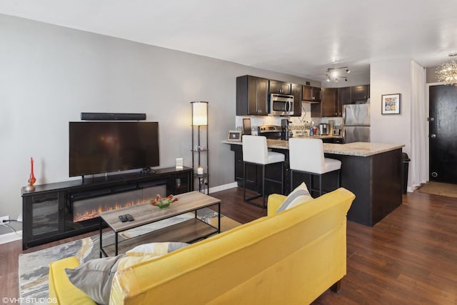 living room featuring dark wood-style floors, baseboards, and a glass covered fireplace