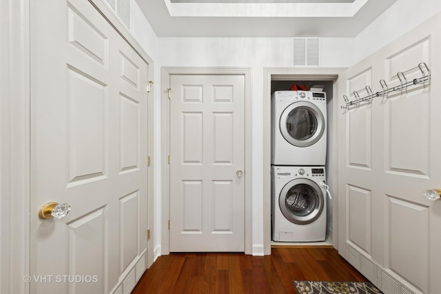 clothes washing area with dark wood-type flooring, stacked washer / drying machine, and a skylight