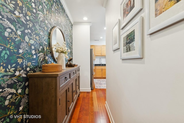 hallway with sink, hardwood / wood-style flooring, and crown molding