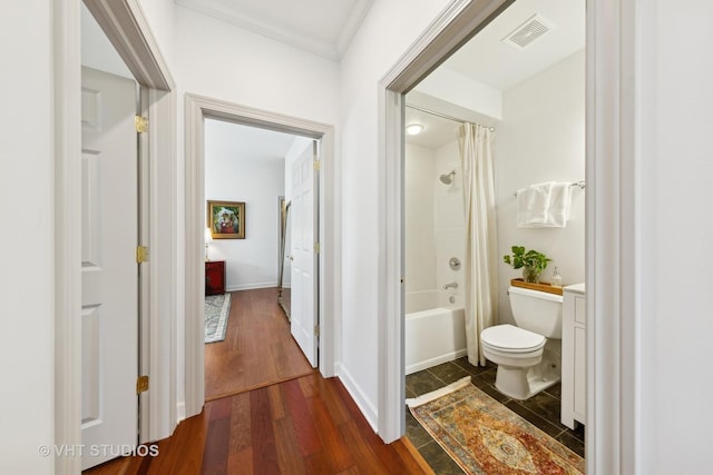 hallway with ornamental molding and dark wood-type flooring