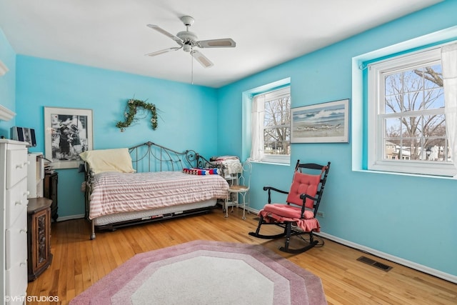 bedroom with visible vents, wood-type flooring, baseboards, and ceiling fan