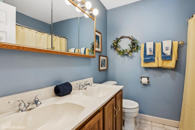 bathroom featuring a sink, baseboards, toilet, and double vanity