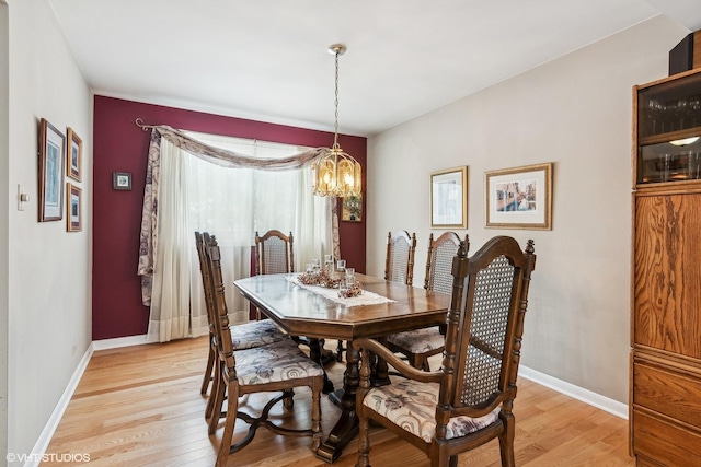 dining space with light wood finished floors, a chandelier, and baseboards