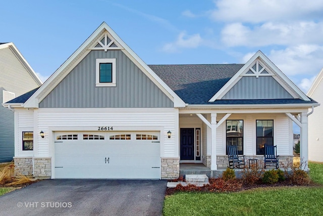 craftsman-style house with driveway, a porch, a garage, stone siding, and board and batten siding