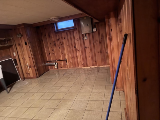 basement with light tile patterned floors, electric panel, and wooden walls