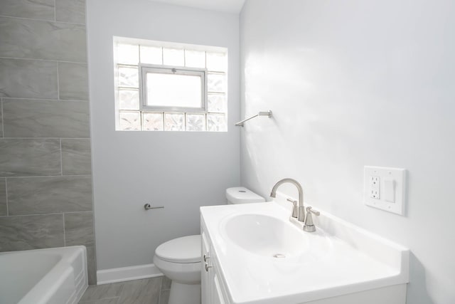 bathroom featuring toilet, a tub to relax in, and vanity