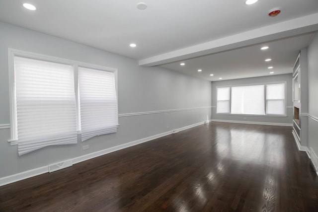 spare room featuring dark wood-type flooring and beamed ceiling