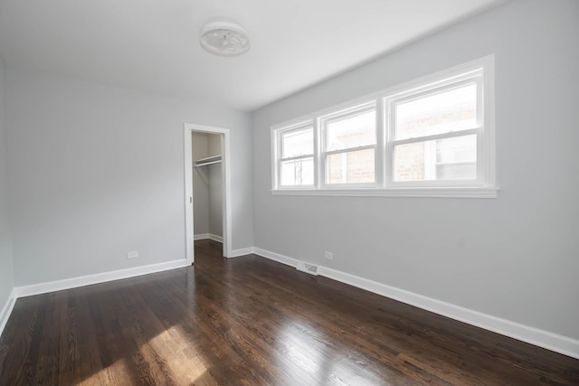 unfurnished bedroom featuring dark hardwood / wood-style floors, a walk in closet, and a closet