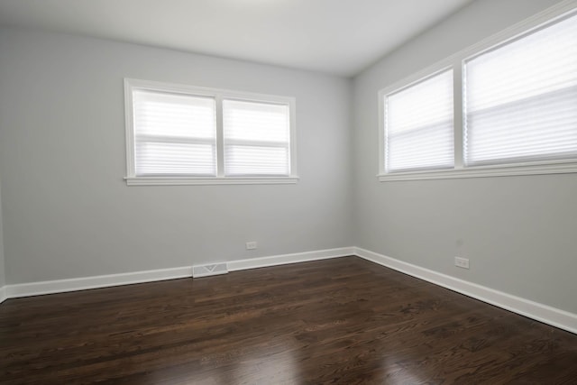 unfurnished room with plenty of natural light and dark wood-type flooring