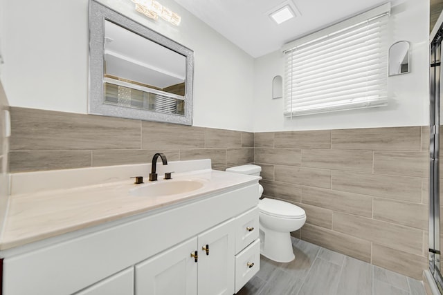 bathroom featuring toilet, tile walls, vanity, and an enclosed shower