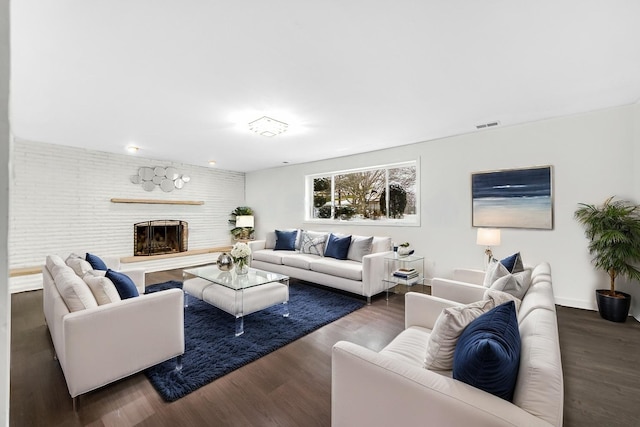 living area featuring a large fireplace, visible vents, and wood finished floors