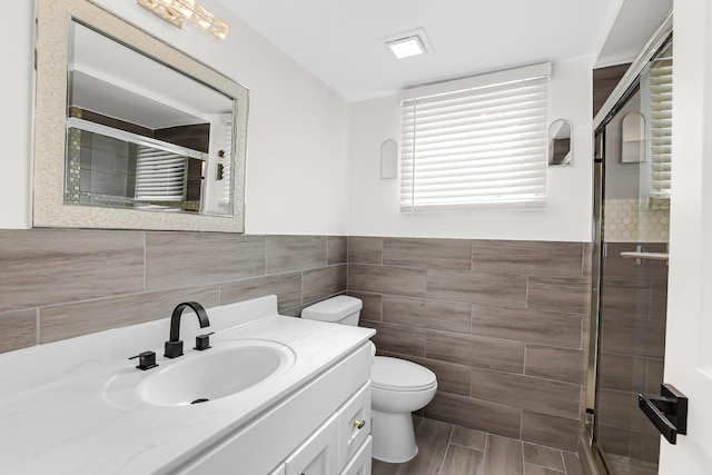 bathroom with toilet, tile walls, vanity, and walk in shower