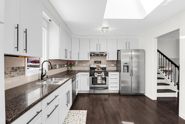 kitchen featuring appliances with stainless steel finishes, dark wood-type flooring, sink, white cabinetry, and dark stone countertops