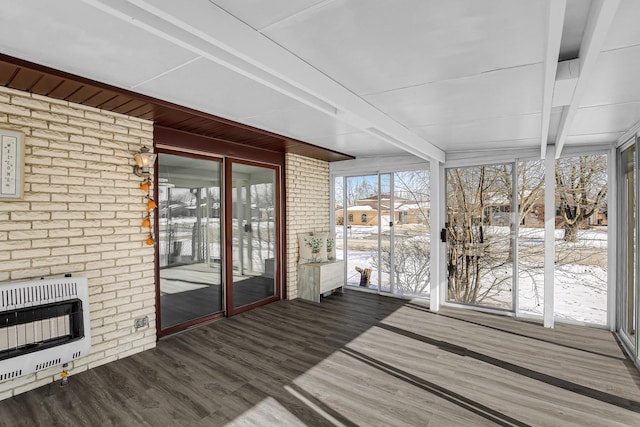 unfurnished sunroom featuring heating unit and beamed ceiling