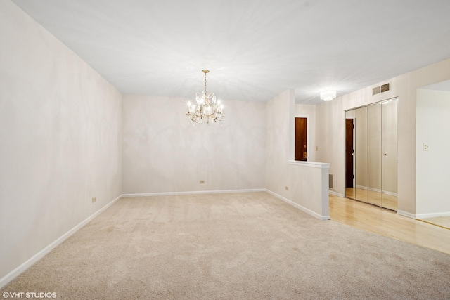 empty room featuring a chandelier, baseboards, visible vents, and carpet flooring