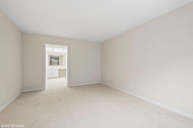 unfurnished room featuring light carpet and baseboards